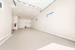 Spacious garage with light-colored flooring, white walls, and multiple windows providing natural illumination
