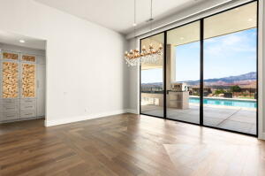 Expansive sliding glass doors opening to an outdoor patio with a swimming pool, complemented by wood-finish flooring in a herringbone pattern