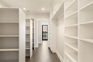 Hallway featuring extensive built-in white shelving, recessed lighting, wood-finish flooring, and a black-framed glass door