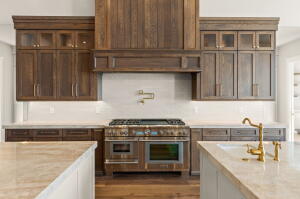 Gourmet kitchen featuring a wood-paneled range hood, professional-grade stainless steel range with double ovens, ample wood cabinetry, light-toned countertops, and a white tile backsplash