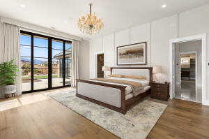 Spacious room featuring wide plank wood-finish flooring, a contemporary chandelier, and large glass panel doors opening to an outdoor patio