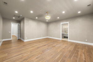 Spacious room featuring wood-finish flooring, recessed lighting, and a decorative chandelier