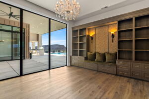 Expansive room featuring wood-finish flooring, a built-in shelving system with integrated seating, and large sliding glass doors
