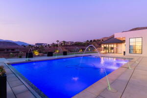 Outdoor swimming pool with integrated water features, surrounded by a light-toned paved patio