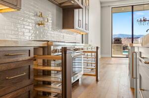 Gourmet kitchen with professional-grade stainless steel range, light wood-finish flooring, and expansive floor-to-ceiling windows