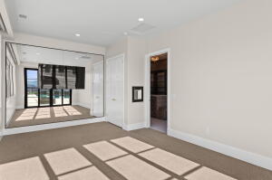 Carpeted room featuring a mirrored wall and two white doors