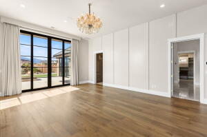 Spacious room featuring wood-finish flooring, a large glass multi-panel door with mountain scenery, a decorative chandelier, recessed lighting, and white panel accent walls
