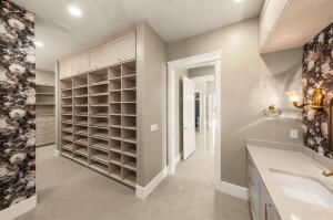 Custom walk-in closet featuring extensive built-in shelving, overhead cabinetry, and recessed lighting