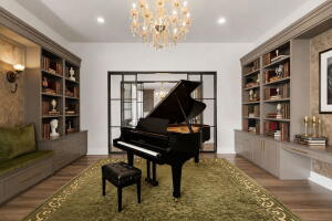 White walls with recessed lighting and a central chandelier illuminate this room featuring built-in shelving, a window bench with a green cushion, and wood-finish flooring