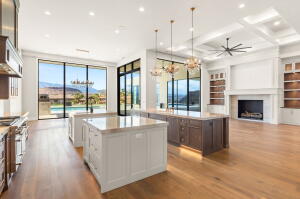 Open-concept living area with wood-finish flooring, a coffered ceiling, and a prominent fireplace with built-in shelving