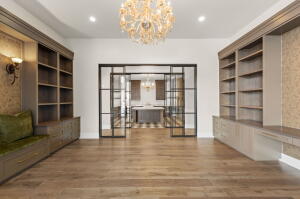 Open-concept living space with wood-finish flooring, a decorative chandelier, recessed lighting, and built-in shelving with integrated cabinetry