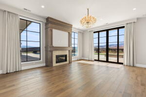 Spacious room featuring light wood-finish flooring and a central fireplace with an ornate wood mantle and light stone surround