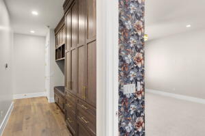 Hallway featuring wood-finish flooring, recessed lighting, and built-in wood cabinetry with gold-tone hardware and integrated seating