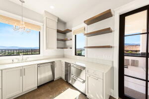 Bright kitchen area featuring white cabinetry, light countertops, wood-finish flooring, stainless steel appliances, and large windows with mountain scenery