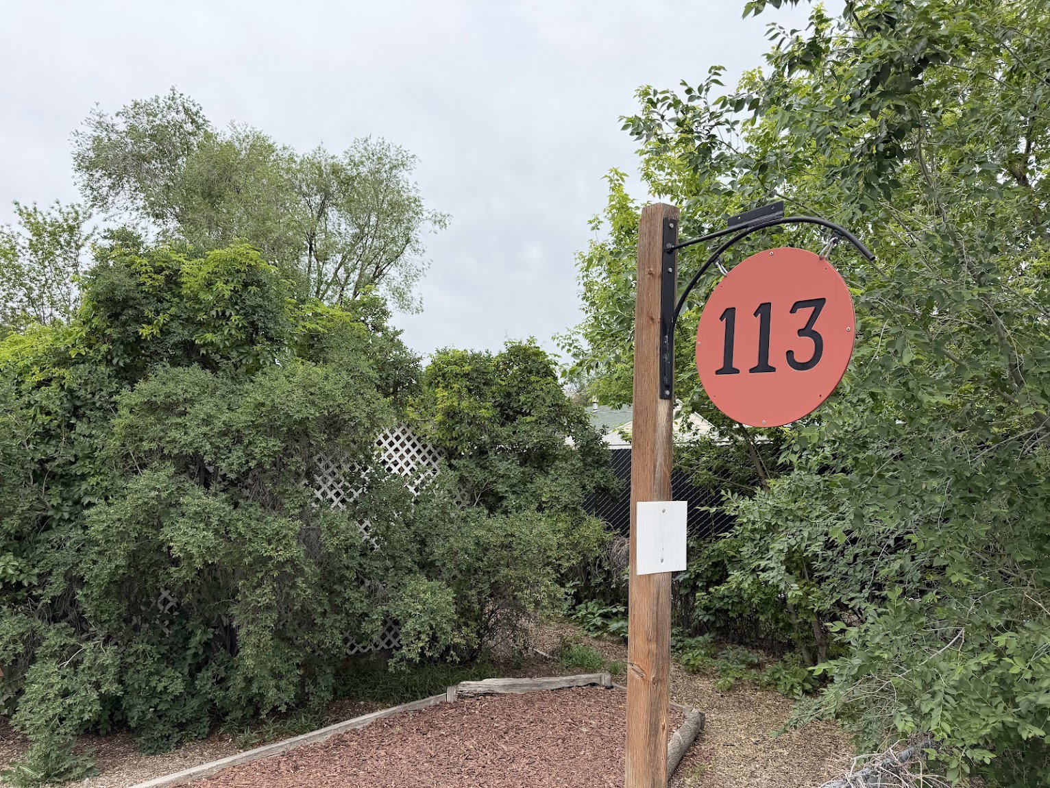 Outdoor signpost featuring a circular coral-colored address plaque with black numbering