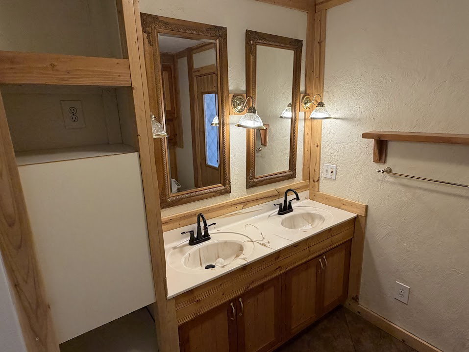 Dual vanity with integrated sinks, wood-finish cabinetry, and framed mirrors