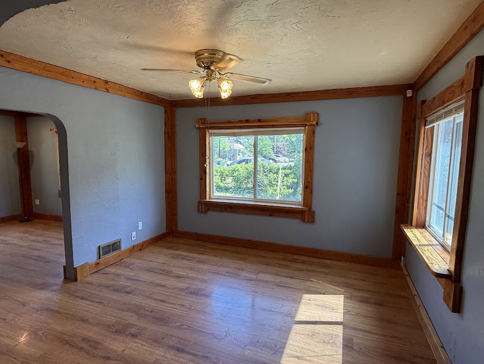 Spacious interior featuring wood-finish flooring, natural wood trim, and a ceiling fan with integrated lighting