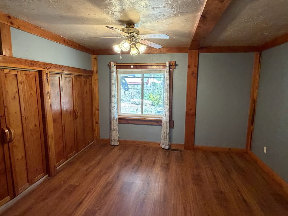 Room featuring wood-finish flooring, exposed wood beams, and built-in wood-paneled cabinetry