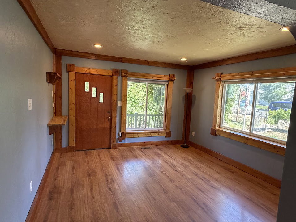 Spacious room featuring wood-finish flooring, light blue walls, and natural wood trim throughout