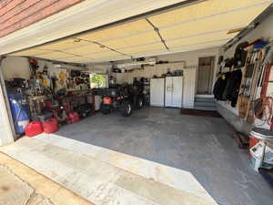 Spacious garage with concrete flooring, integrated cabinetry, and built-in shelving