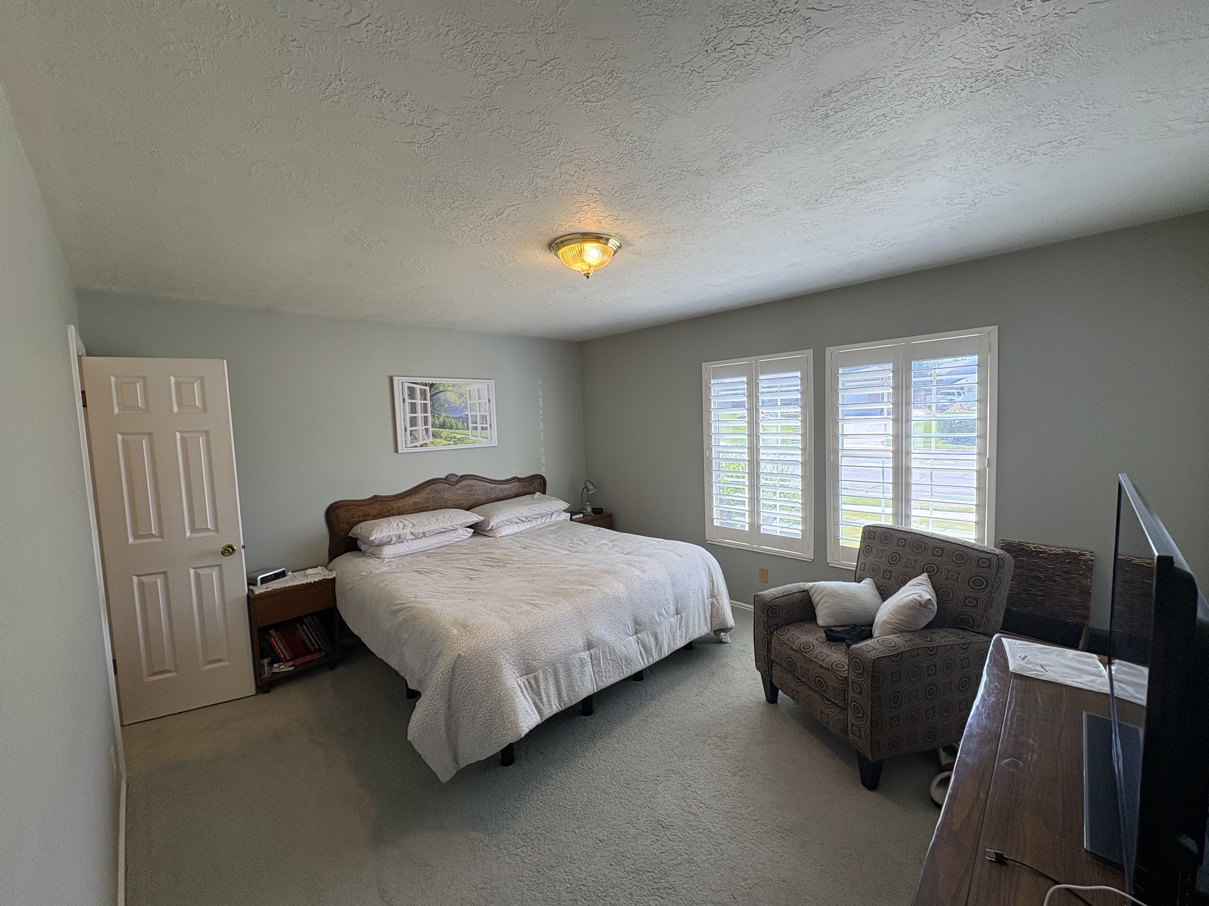 Interior room featuring neutral wall color, carpet flooring, a six-panel door, and twin windows with white plantation shutters