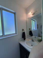 Bathroom vanity featuring a white oval sink, chrome faucet, and a dark wood-finish cabinet
