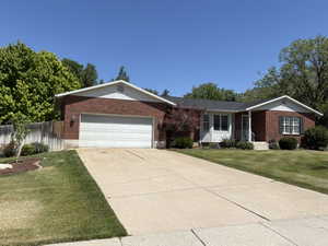 Brick and siding exterior featuring a two-car garage, concrete driveway, and front lawn