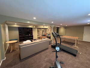 Finished basement featuring recessed lighting, a built-in entertainment center, and a natural stone accent wall