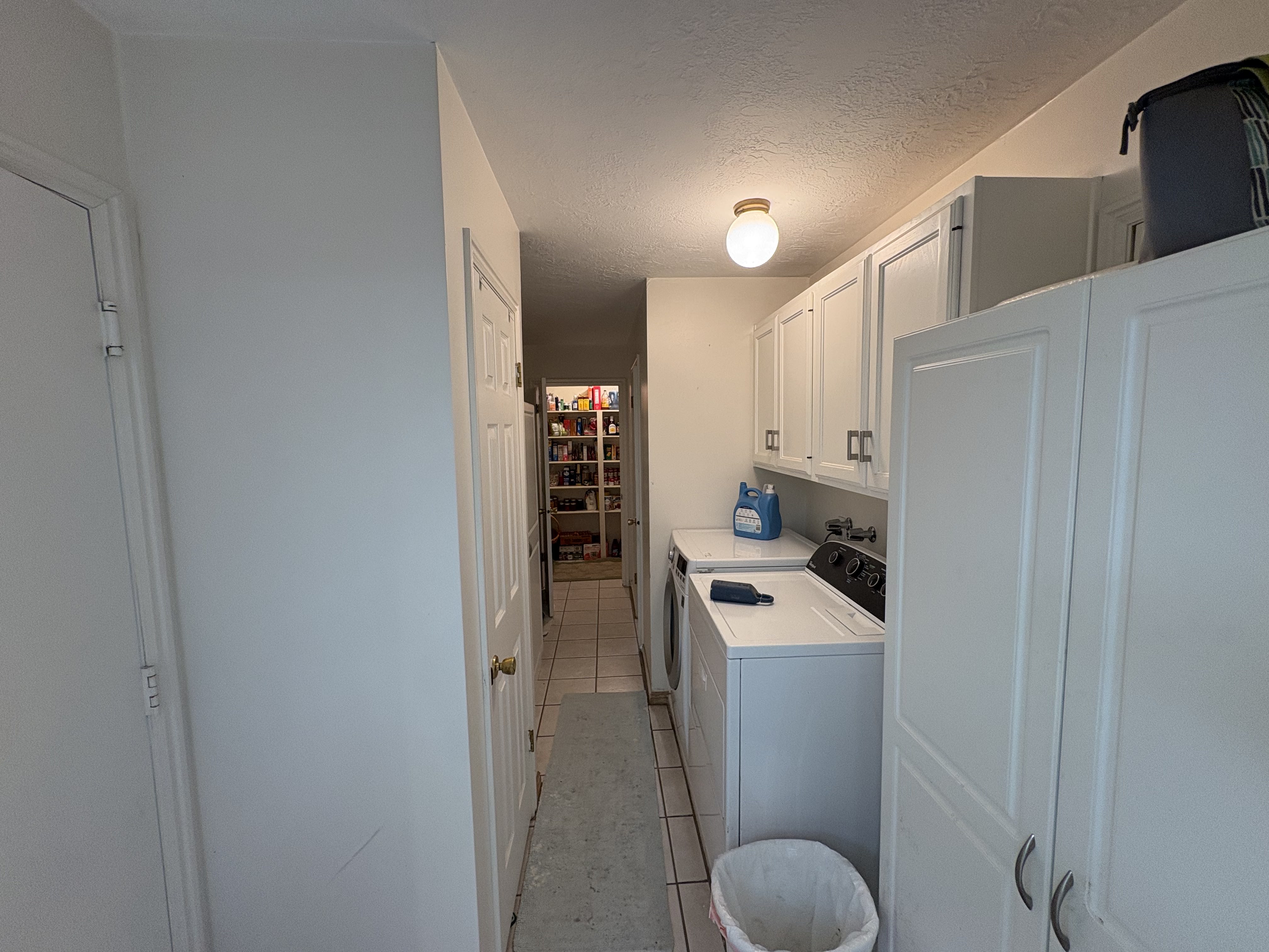 Laundry area featuring white cabinetry, a built-in countertop, and tile flooring
