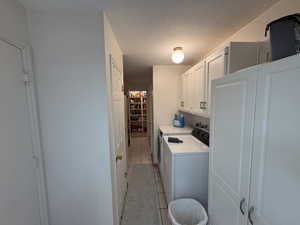 Laundry area featuring white cabinetry, a built-in countertop, and tile flooring