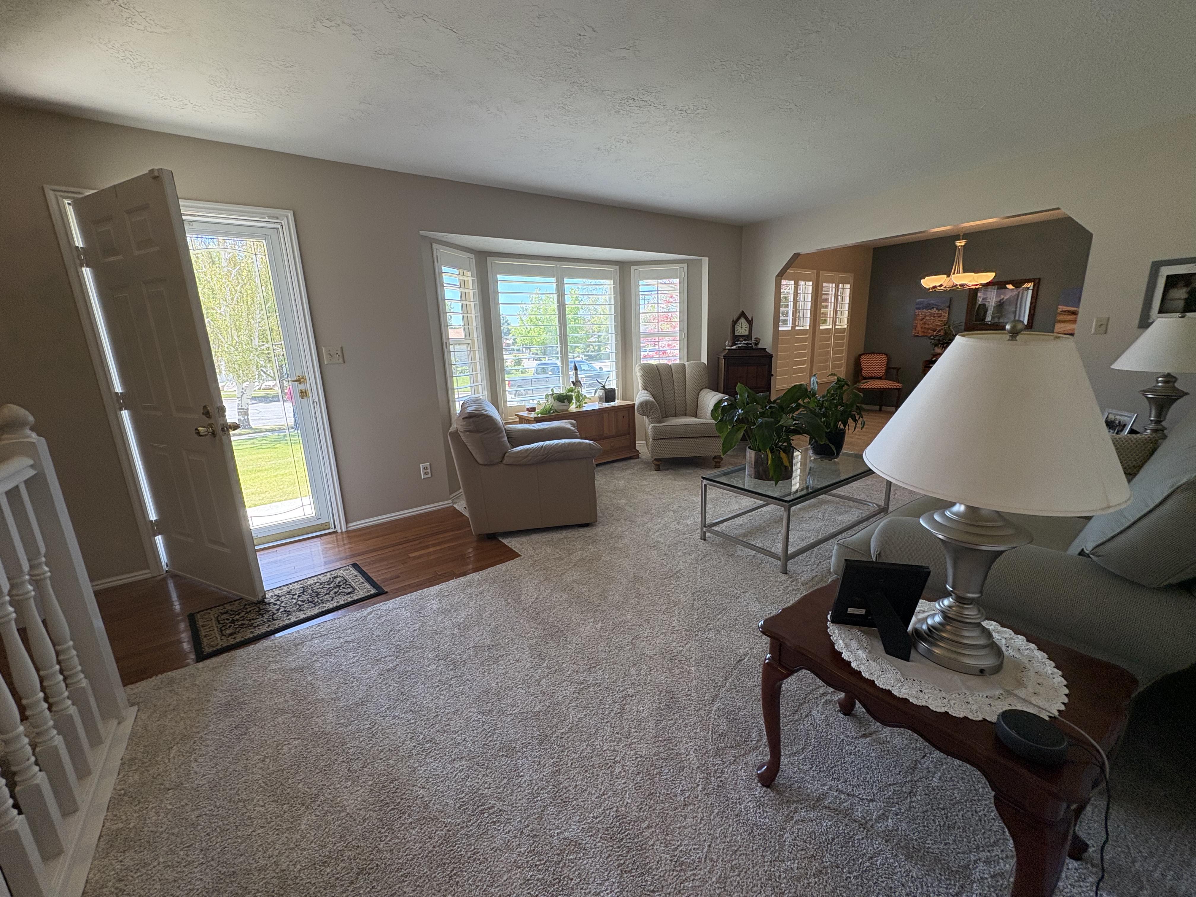 Living area featuring carpeting, bay windows, wood-finish flooring at the entry, and an arched doorway