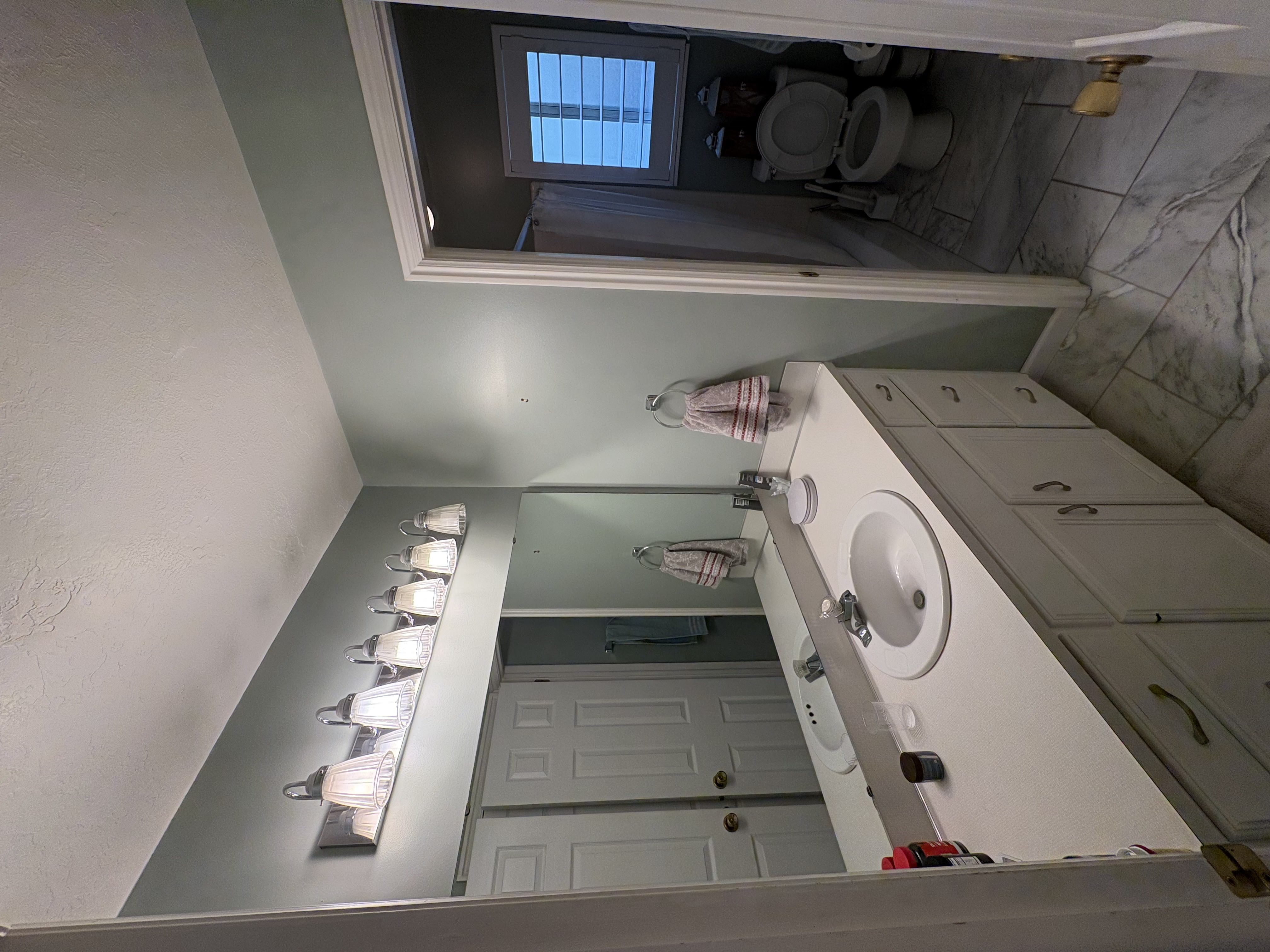 Bathroom vanity featuring a single-basin sink, white countertop, and white cabinetry