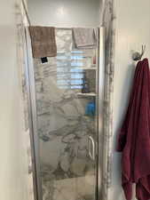 Walk-in shower featuring glass enclosure with a metal handle and frame