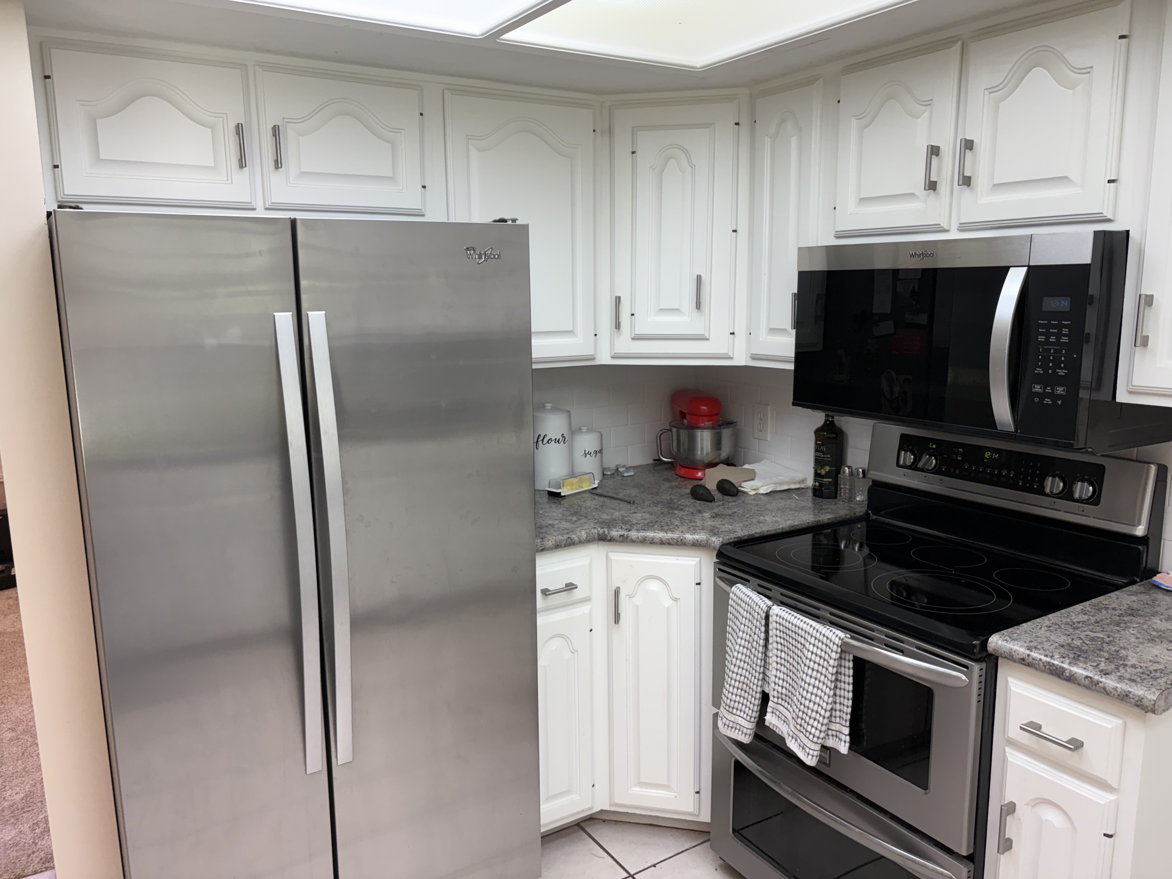 Kitchen featuring white cabinetry, grey countertops, stainless steel side-by-side refrigerator, stainless steel electric range, and stainless steel microwave