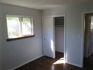 Room featuring wood-finish flooring, a double-paned window with a wood sill, and a closet with sliding doors