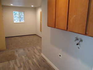 Kitchenette area featuring wood cabinetry, plumbing rough-ins for a washer and dryer, and wood-finish flooring