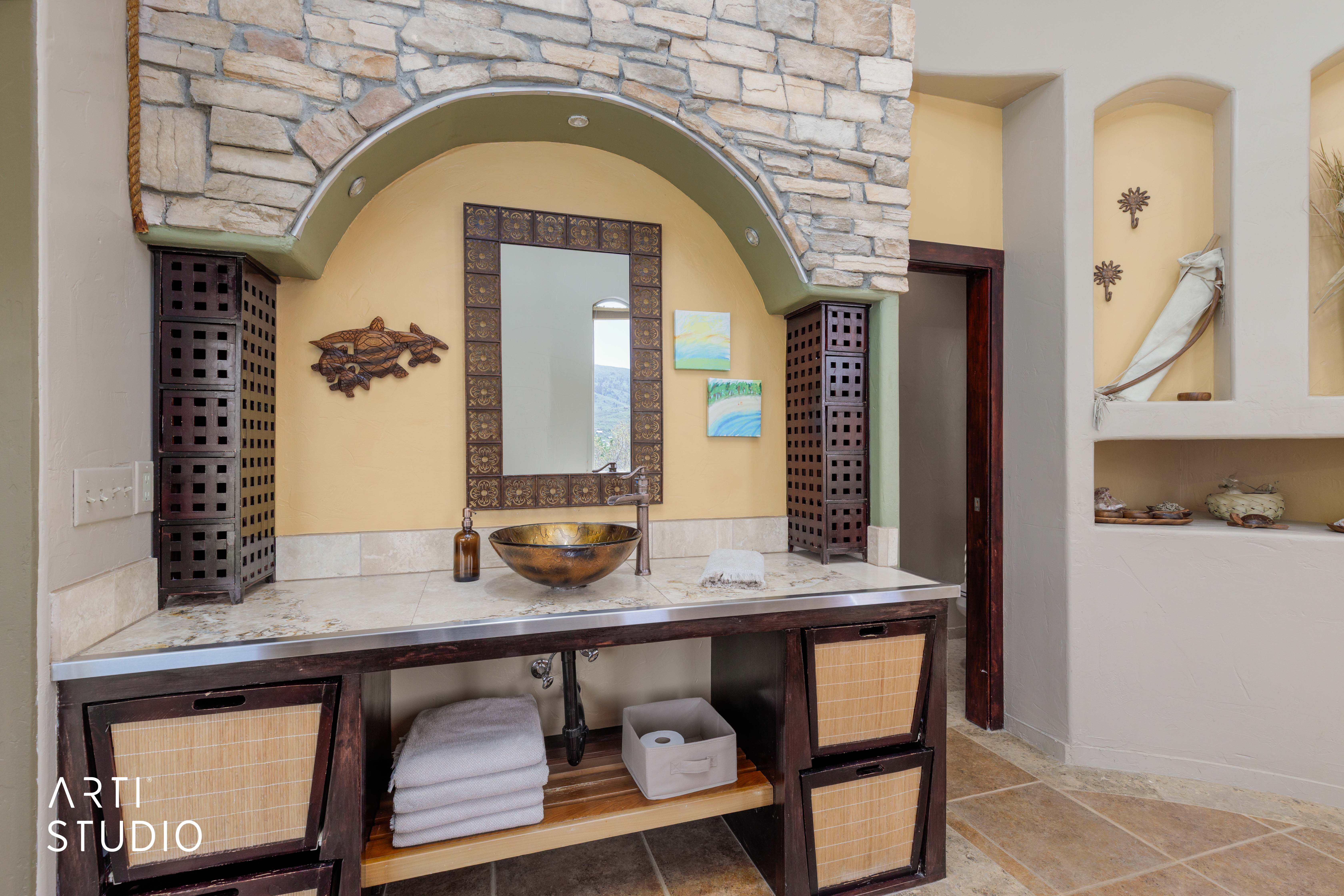 Bathroom vanity featuring an ornate mirror, vessel sink, and stone countertop