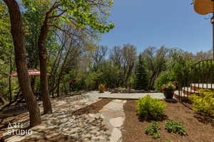 Flagstone patio with a stone retaining wall, surrounded by mature trees and lush landscaping