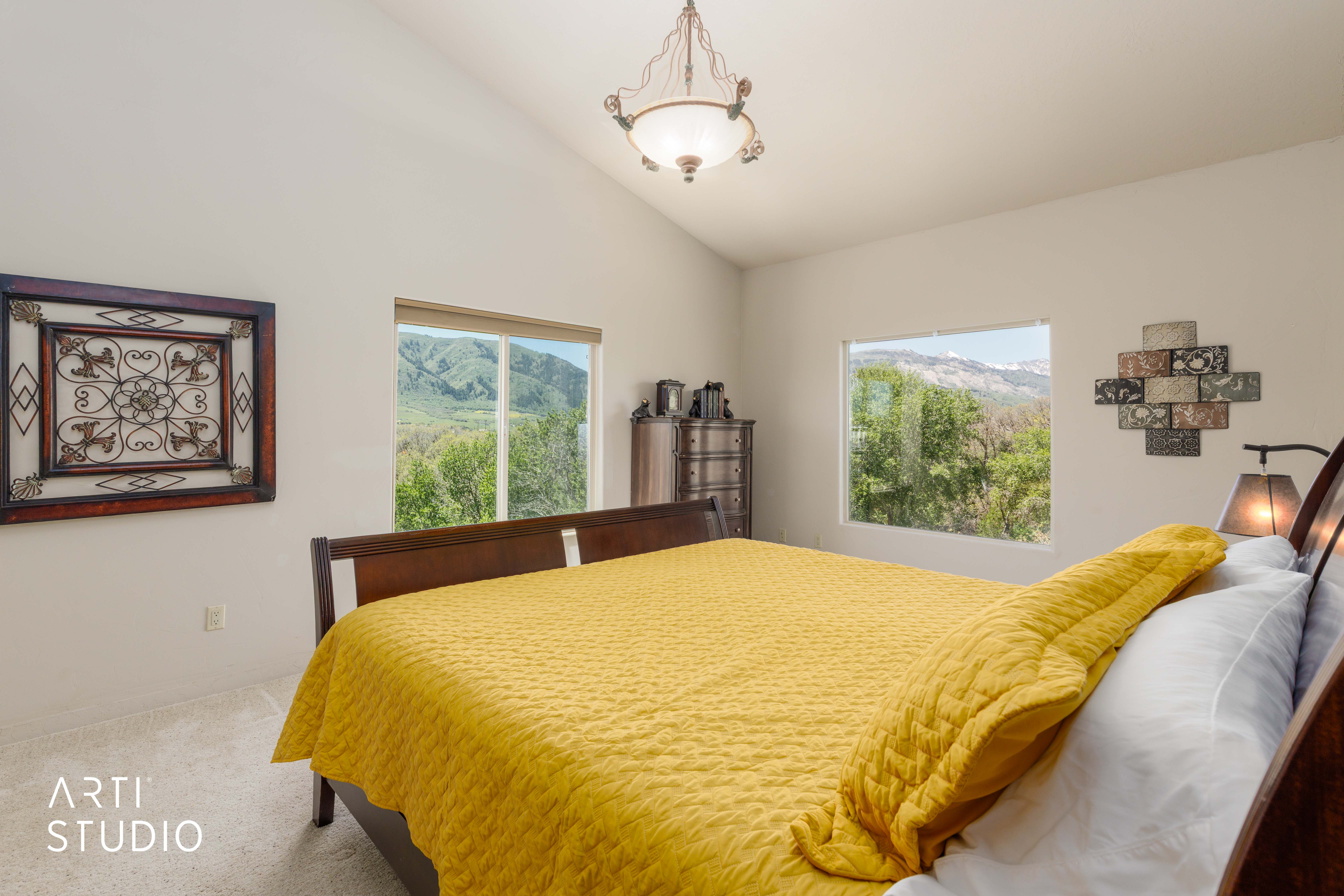 Vaulted ceiling bedroom featuring carpet flooring and a central chandelier