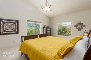 Vaulted ceiling bedroom featuring carpet flooring and a central chandelier