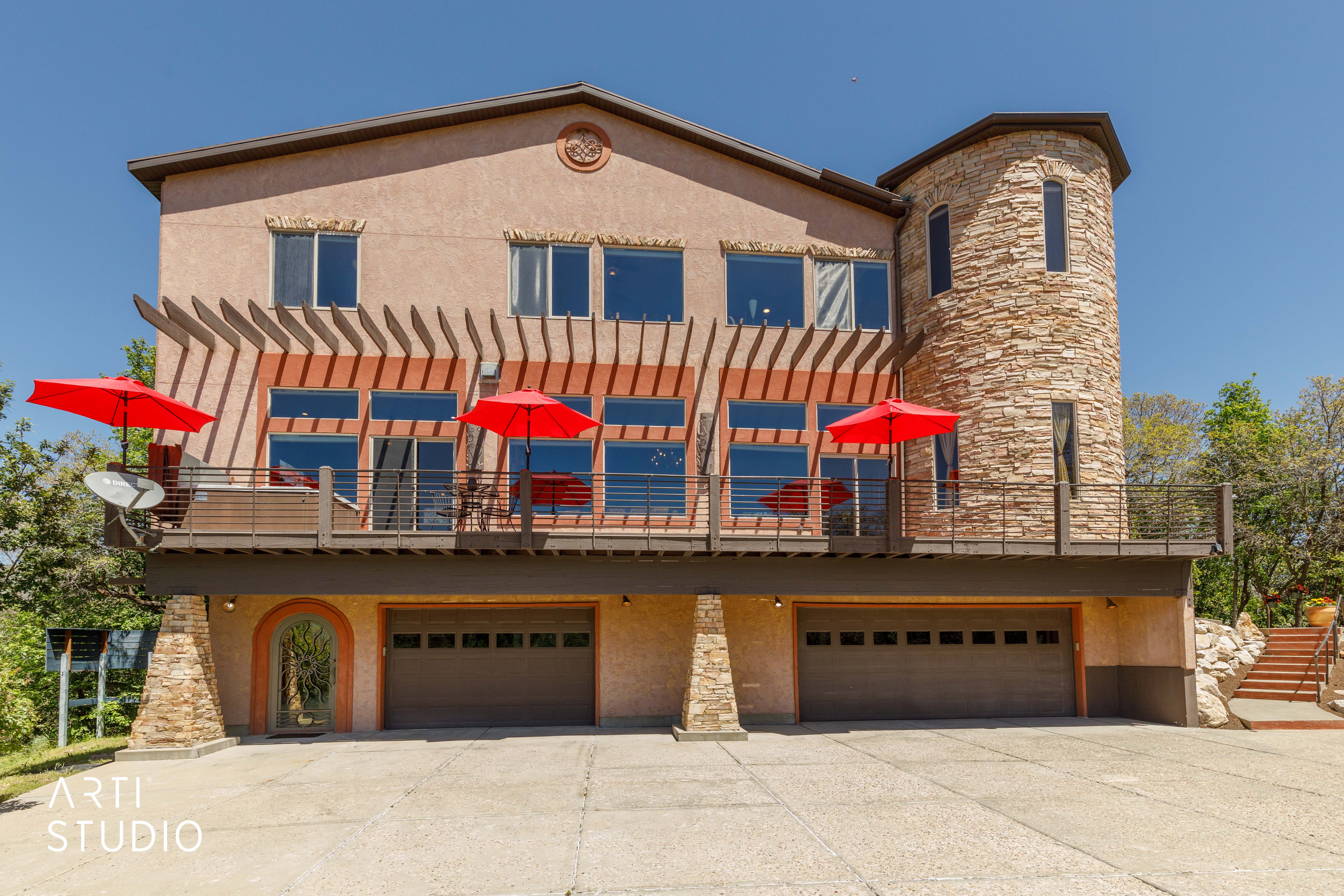 Stucco exterior featuring a stone accent tower and a full-width upper deck with a pergola