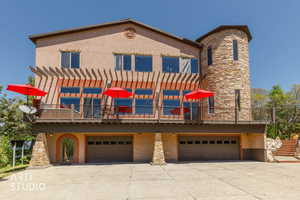 Stucco exterior featuring a stone accent tower and a full-width upper deck with a pergola
