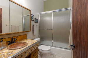 Bathroom featuring a stone vessel sink, patterned stone vanity countertop, bronze-finish faucet, and a large mirrored medicine cabinet