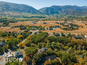 Expansive mountain landscape featuring a valley with residential properties, natural foliage, and distant peaks