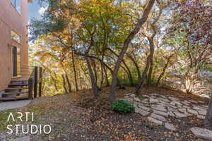 Terraced outdoor space featuring a flagstone patio, mature trees, and natural landscaping