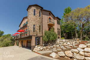 Stucco exterior with a stone-clad turret, featuring multiple arched windows and a Juliet balcony