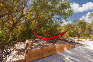 Tiered wood decking with natural wood tones, surrounded by mature trees, features a flagstone patio with a built-in fire pit