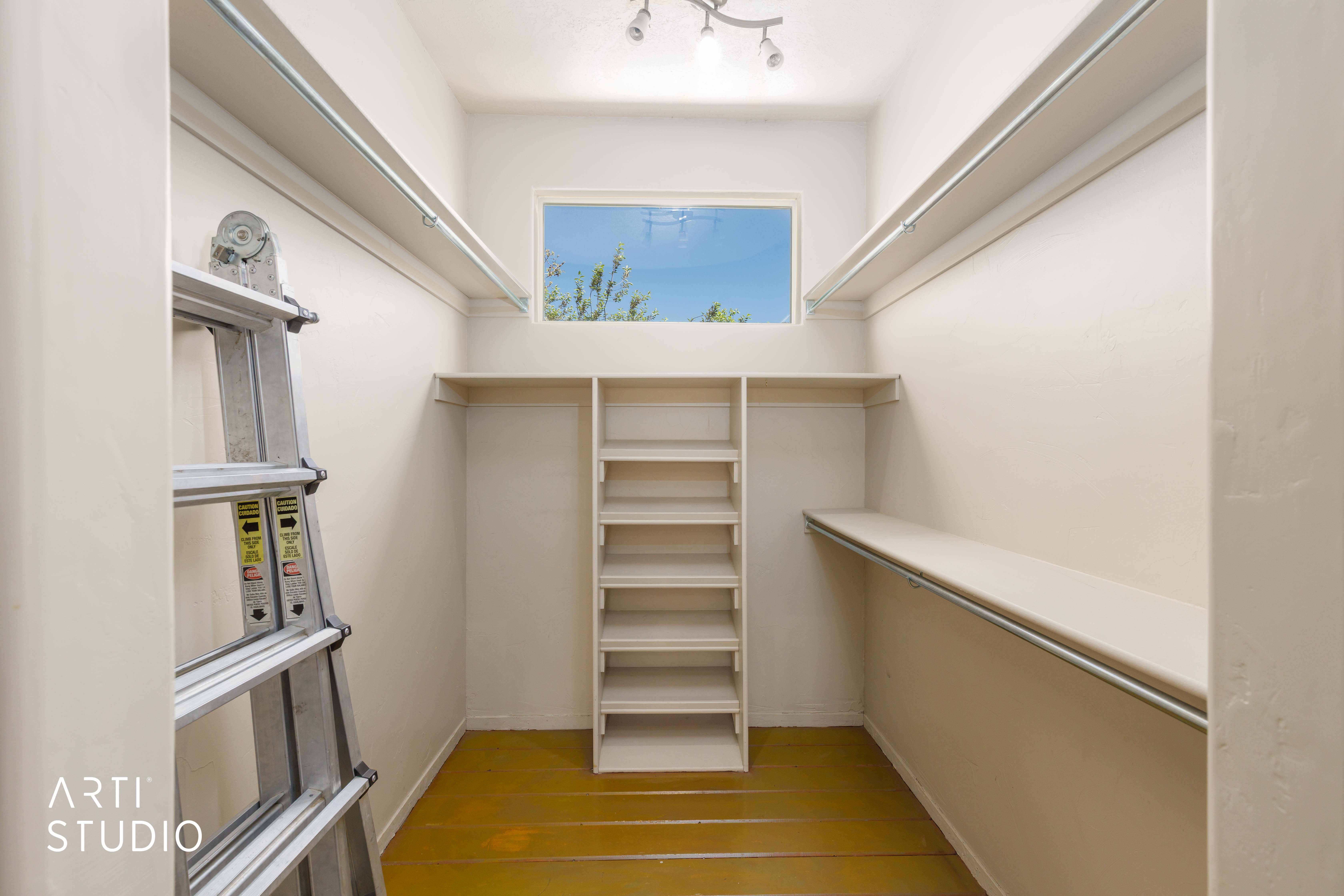 Walk-in closet featuring built-in shelving, hanging rods, an upper window, and track lighting