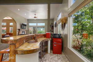 Curved wet bar with a built-in copper sink, wood-finish flooring, recessed lighting, and a window wall