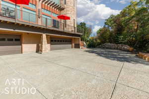 Expansive concrete driveway leading to a multi-car garage with panel doors